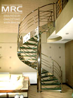 Winding metalic staircase with a central supporting bar and bow-string. Framework and baluster of staircase
from polished stainless steel, stages from tempered glass